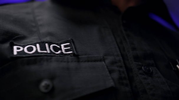 Details of black police uniform. Policeman holding walkie talkie in pocket - Photo, Image