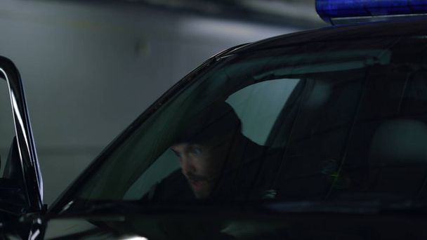 Полицейский стоит за дверью полицейской машины. Коп целится в полицейскую машину. - Фото, изображение