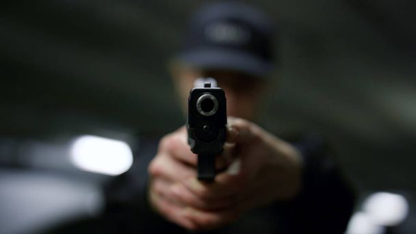 Polizistin mit Waffe in der Hand. Polizistin richtet Pistole auf Kamera - Foto, Bild