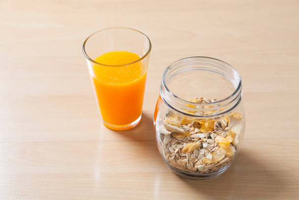 Frühstückszerealien im Glas. Gesundes Müsli mit Haferflocken, Nüssen und Rosinen auf Holztisch. - Foto, Bild