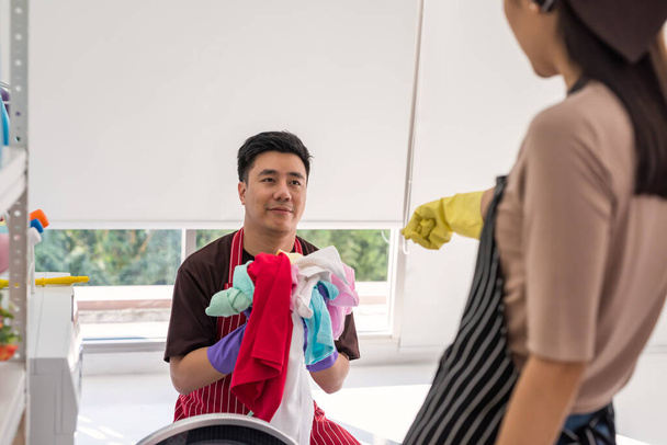 Joven esposa mandona mandar a su marido a lavar muchas toallas. Lástima asiático hombre fuerza a hacer el trabajo doméstico por su chica. - Foto, Imagen