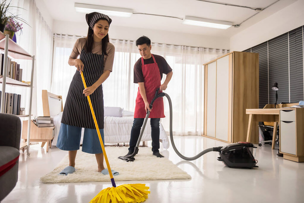 掃除機とマップを使用して幸せなアジアの若いカップルは、家の寝室をきれいにします。衛生と医療ライフスタイルの概念。新しい家やアパートに移動した後の洗浄. - 写真・画像