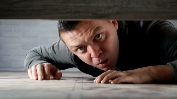 Człowiek ukrywający się pod łóżkiem przed ścigaczem, rabuś  - Materiał filmowy, wideo