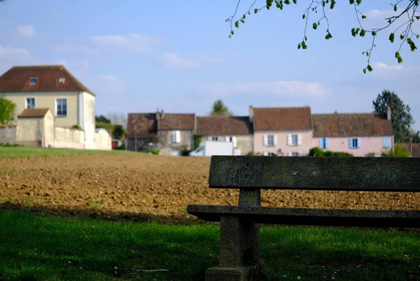 Una panchina solitaria e un piccolo villaggio sullo sfondo in Francia - Foto, immagini