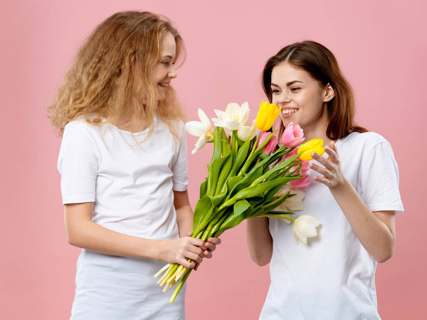 Mamá e hija camisetas ramo flores regalo rosa fondo - Foto, imagen