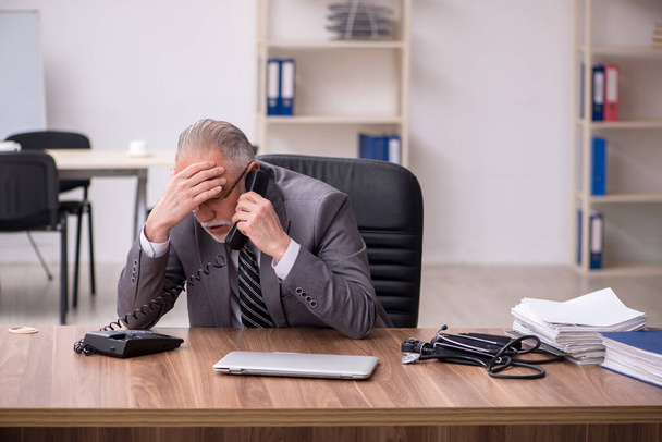 Aged male employee suffering at workplace - Foto, Bild