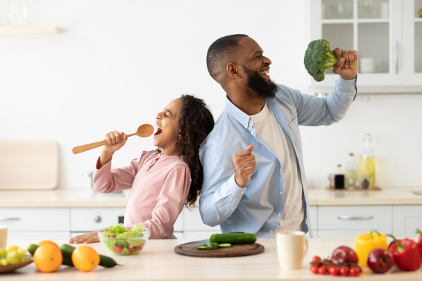 Musta isä ja tytär laulavat keittiössä hauskaa - Valokuva, kuva