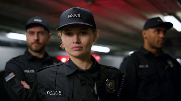 Женщина-полицейский в кепке позирует перед камерой. Офицер полиции смотрит в камеру  - Фото, изображение