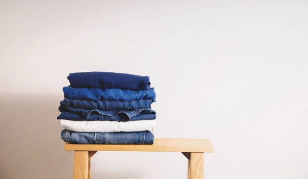 Clothes Concept. Stack of Clothing on Wooden bench by the Whaite Wall. Blue Navy Tone - Foto, immagini