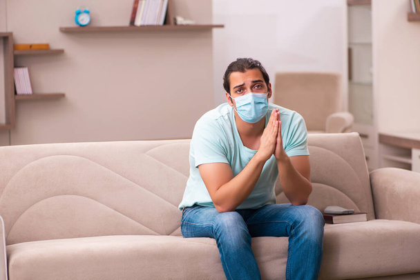 Jeune homme assis à la maison pendant la pandémie - Photo, image