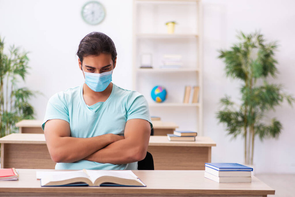 Young male student sitting in the classroom wearing mask - Photo, Image