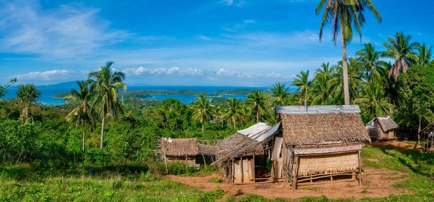 Un petit village sur une belle île tropicale, avec les maisons de chaume traditionnelles appartenant au peuple Mangyan indigène, qui vivent à l'intérieur des terres dans les zones montagneuses de l'île de Mindoro aux Philippines. - Photo, image