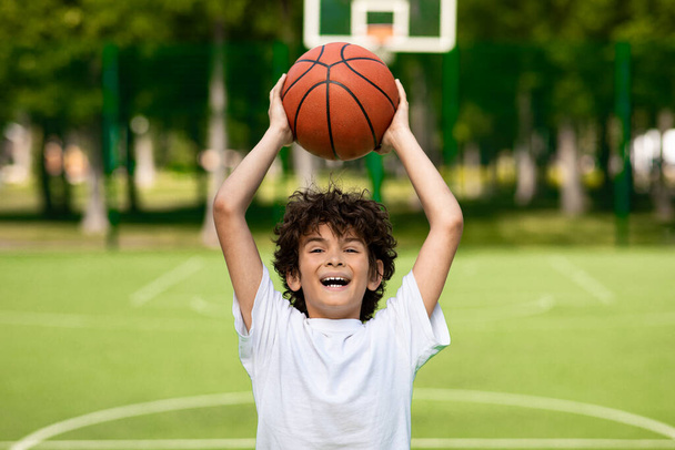 Portrét sportovního kudrnatého chlapce házet koš míč - Fotografie, Obrázek