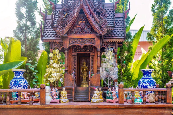 Közelkép egy thai szellemházról, egy hagyományos építmény kis másolatáról, ahol az ingatlan istensége vagy szellemi őrzője él és áldozik fel magát, valamint a spirituális kísérőket ábrázoló figurákról.. - Fotó, kép