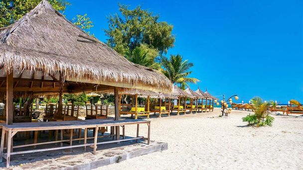 Île tropicale idyllique. Une belle plage publique de sable blanc avec des cabanes rustiques sur le toit de chaume pour les touristes sur Gili Air Island, Indonésie. - Photo, image