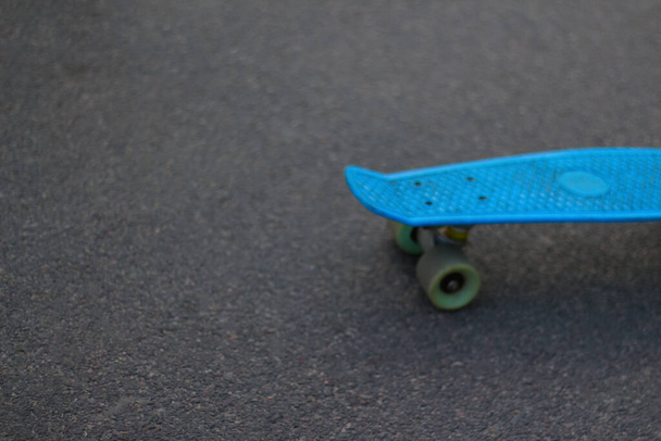 Defocus close up blue skateboard at park. Head of skateboard and wheel on road at public park. Sport concept. Blurred bokeh. Modern backdrop. Cold tint. No focus. Out of focus. - Photo, Image