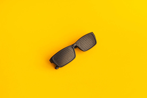 Gözleri iyileştirmek için gözlük. Sarı arkaplanda siyah plastik gözlük - Fotoğraf, Görsel