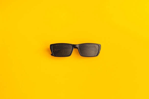 Gözleri iyileştirmek için gözlük. Sarı arkaplanda siyah plastik gözlük - Fotoğraf, Görsel