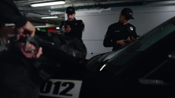 Polizei nimmt Verbrecher auf Parkplatz fest Polizist fesselt Verdächtigen an Streifenwagen - Filmmaterial, Video