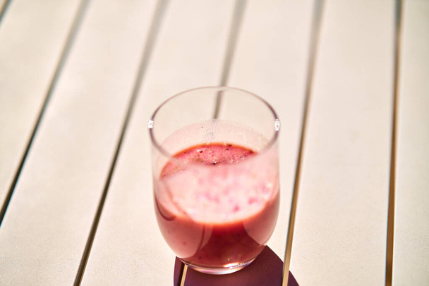 Gyümölcs smoothie piros színű fehér asztal alatt napfény - Fotó, kép
