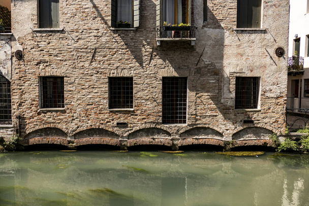 A facade of abeautiful old building with a balcony near calm water in Italy - Foto, Imagem