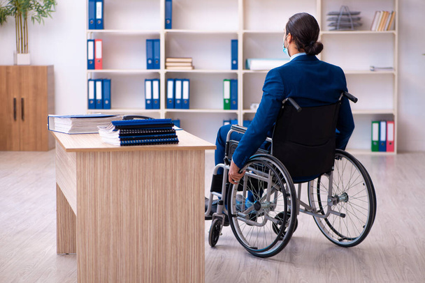 Młody niepełnosprawny pracownik podczas pandemii w miejscu pracy - Zdjęcie, obraz