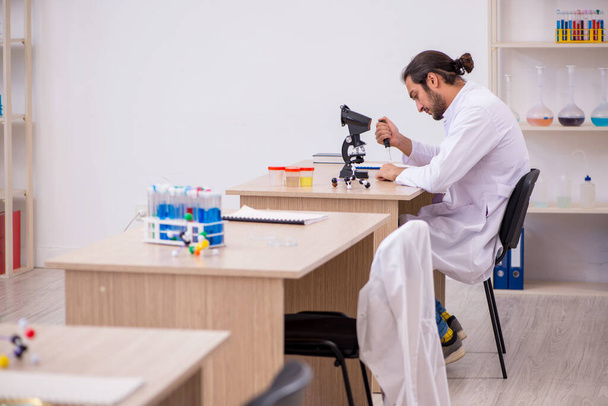Young male chemist sitting at the desk in the classroom - Photo, Image