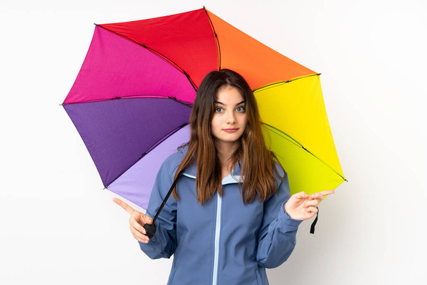 Nainen, jolla on valkoisella pohjalla eristetty sateenvarjo, joka osoittaa jälkipolville epäilevästi - Valokuva, kuva