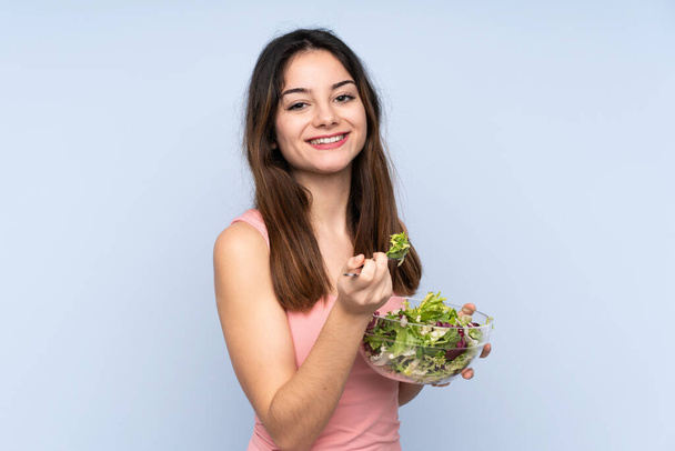 Nuori valkoihoinen nainen tilalla salaatti eristetty sinisellä pohjalla - Valokuva, kuva