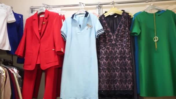 Damespakken en -jurken hangen aan een hanger in een boetiek - Video