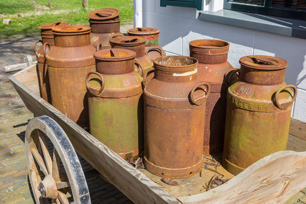 Alte rostige Milchkannen auf einem Holzwagen im historischen Dorf Orvelte, Niederlande - Foto, Bild