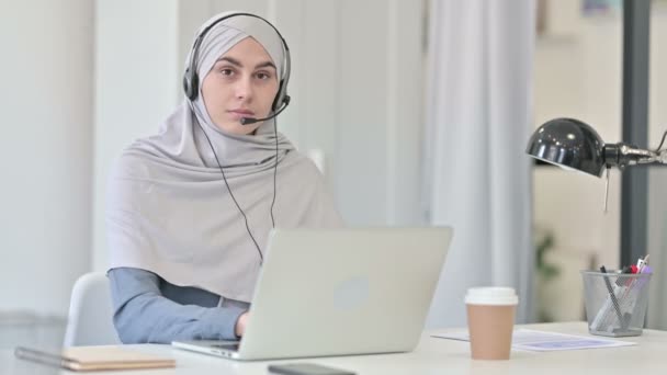 Mujer árabe joven con ordenador portátil sonriendo con auriculares  - Imágenes, Vídeo
