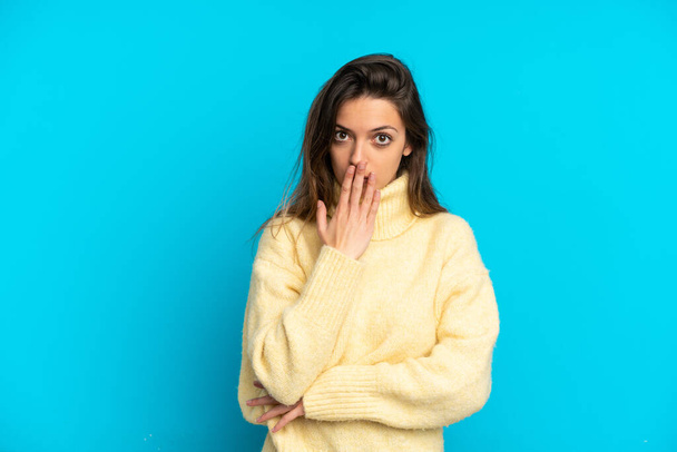 Young caucasian woman isolated on blue background covering mouth with hand - Valokuva, kuva
