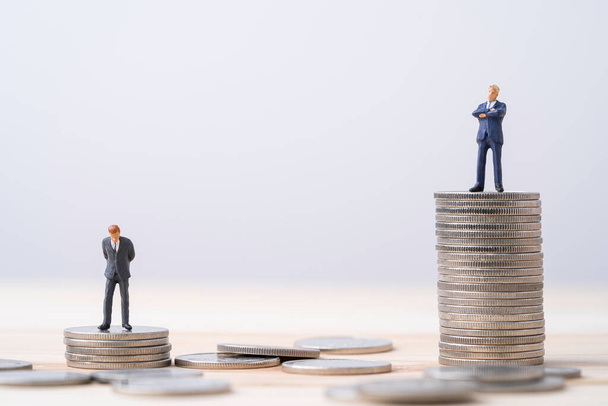 Miniaturní bohatý muž a chudý muž stojící na různých výškových mincí stohování, Nerovné příjmy a platové koncepce. - Fotografie, Obrázek