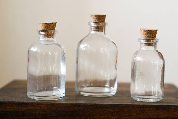 A closeup of the three  glass bottles with corks on the wooden table - Фото, зображення