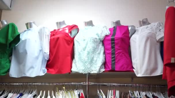 Γυναικείες μπλούζες σε μανεκέν και φόρεμα σε κρεμάστρες στο κατάστημα στην βιτρίνα - Πλάνα, βίντεο