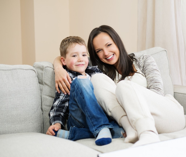 Feliz joven madre con su hijo en un sofá en el interior del hogar
  - Foto, imagen