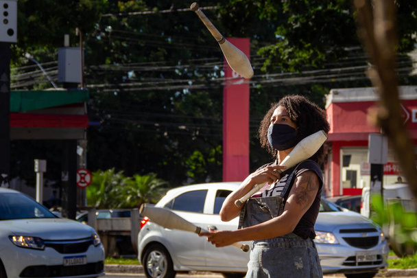 Juggler girl performing at the traffic lights, after the presentation she asks the drivers for a donation. - Photo, Image