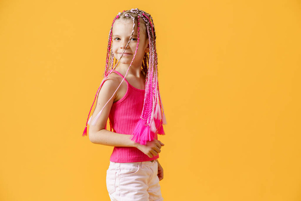 Stylish girl with pink dreadlocks and posing on a yellow backgro - Fotoğraf, Görsel