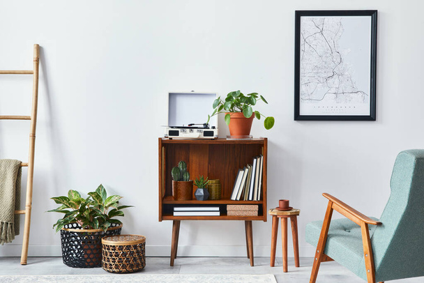 Modern retro composition of living room interior with design wooden cabinet, stylish armchair, mock up poster map, plants, vinyl recorder, books and personal accessories in home decor. Template. - Photo, image