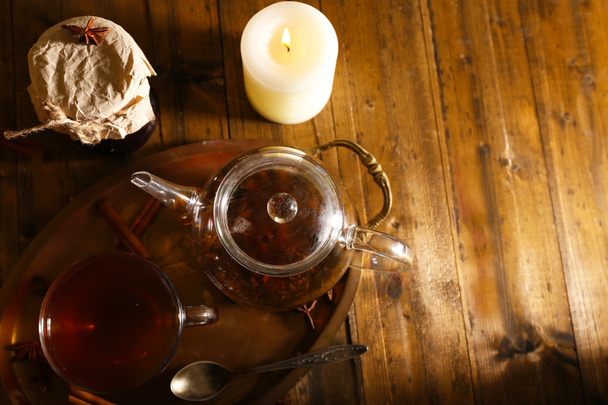 Composition with tea in cup and teapot and candles on table, on wooden background - Foto, afbeelding