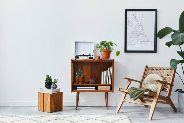 Retro composition of living room interior with mock up poster map, wooden shelf, book, armchair, plant, cacti, vinyl recorder, decoration and personal accessories in stylish home decor. - Foto, Imagen