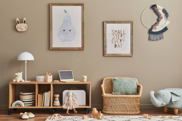 Cozy interior of child room with mint armchair, brown mock up poster frame, toys, teddy bear, plush animal, decoration and hanging cotton colorful balls. Beige wall. Warm kid space. Template. - Foto, afbeelding