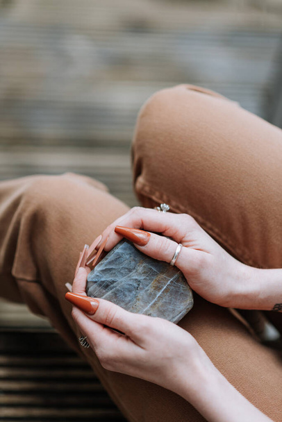 A vertical shot of a female holding a beautiful mineral rock in her hands - Fotó, kép