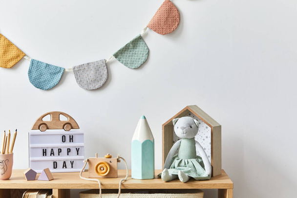 Stylish scandinavian newborn baby room with toys, plush animal, photo camera, dolls and child accessories. Cozy decoration and hanging cotton balls on the white wall. Copy space. - Foto, immagini
