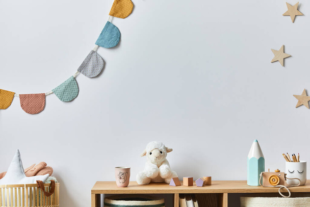 Stylish scandinavian newborn baby room with toys, plush animal, photo camera, doll and child accessories. Cozy decoration and hanging cotton balls on the white wall. Copy space. - Photo, image