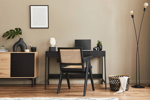 Fancy interiérový design domácích kancelářských prostor se stylovou židlí, psacím stolem, komodou, černým modelovým rámečkem plakátu, lapatopem, knihou, organizátorem psacích stolů a elegantním presonálním příslušenstvím v domácí výzdobě. Šablona.  - Fotografie, Obrázek