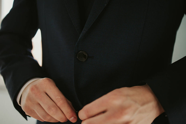 A closeup of a male buttoning his black coat - Φωτογραφία, εικόνα