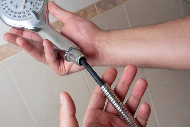 Törött króm zuhany tömlő a férfiak kezében. Hasadék, gumi, szelektív fókusz, zuhanyzóberendezés - Fotó, kép
