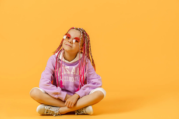 Stylish girl in rounded glasses with pink dreadlocks sitting, lo - Foto, afbeelding